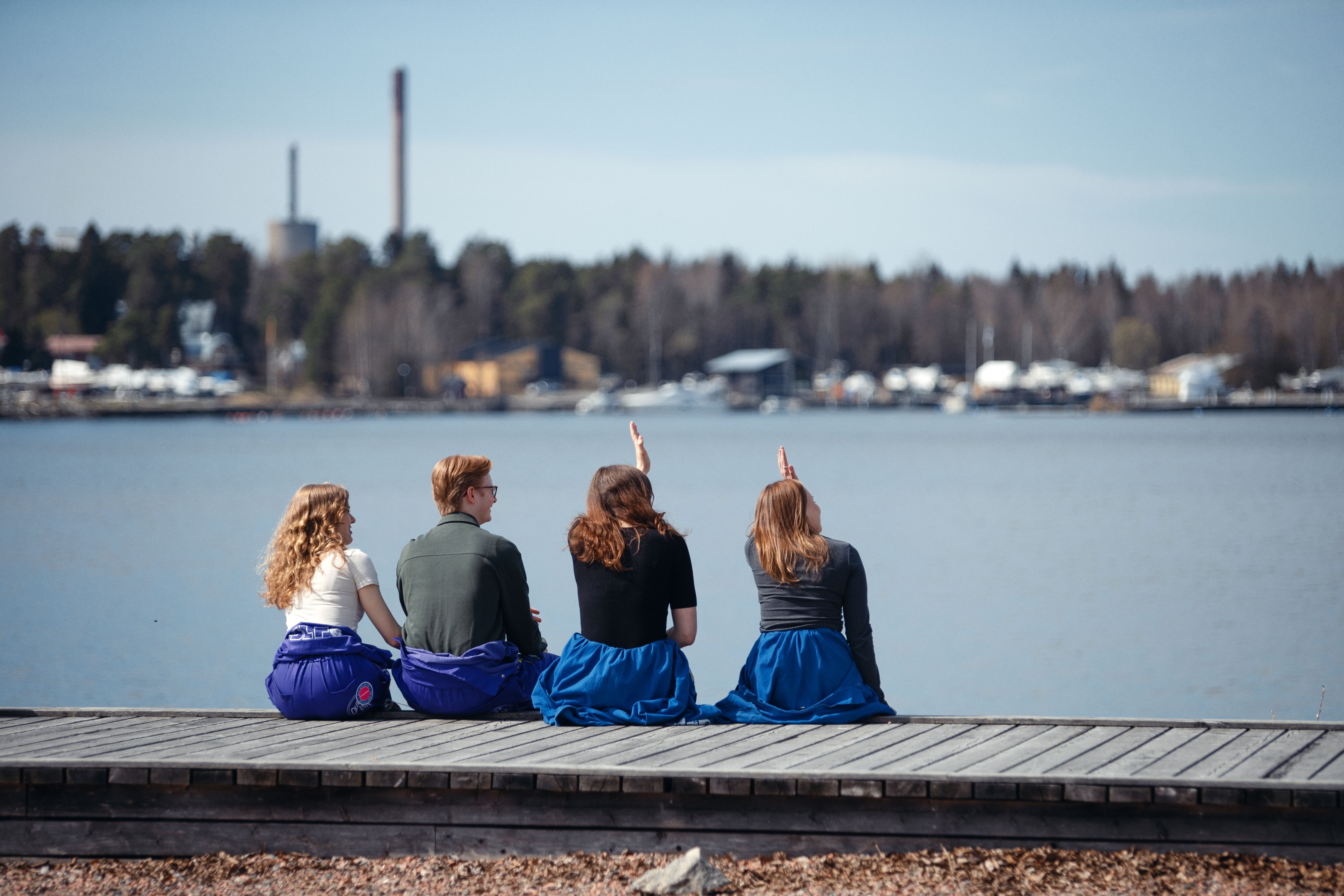 Fyra studerande i blå halare sitter ute nära havet