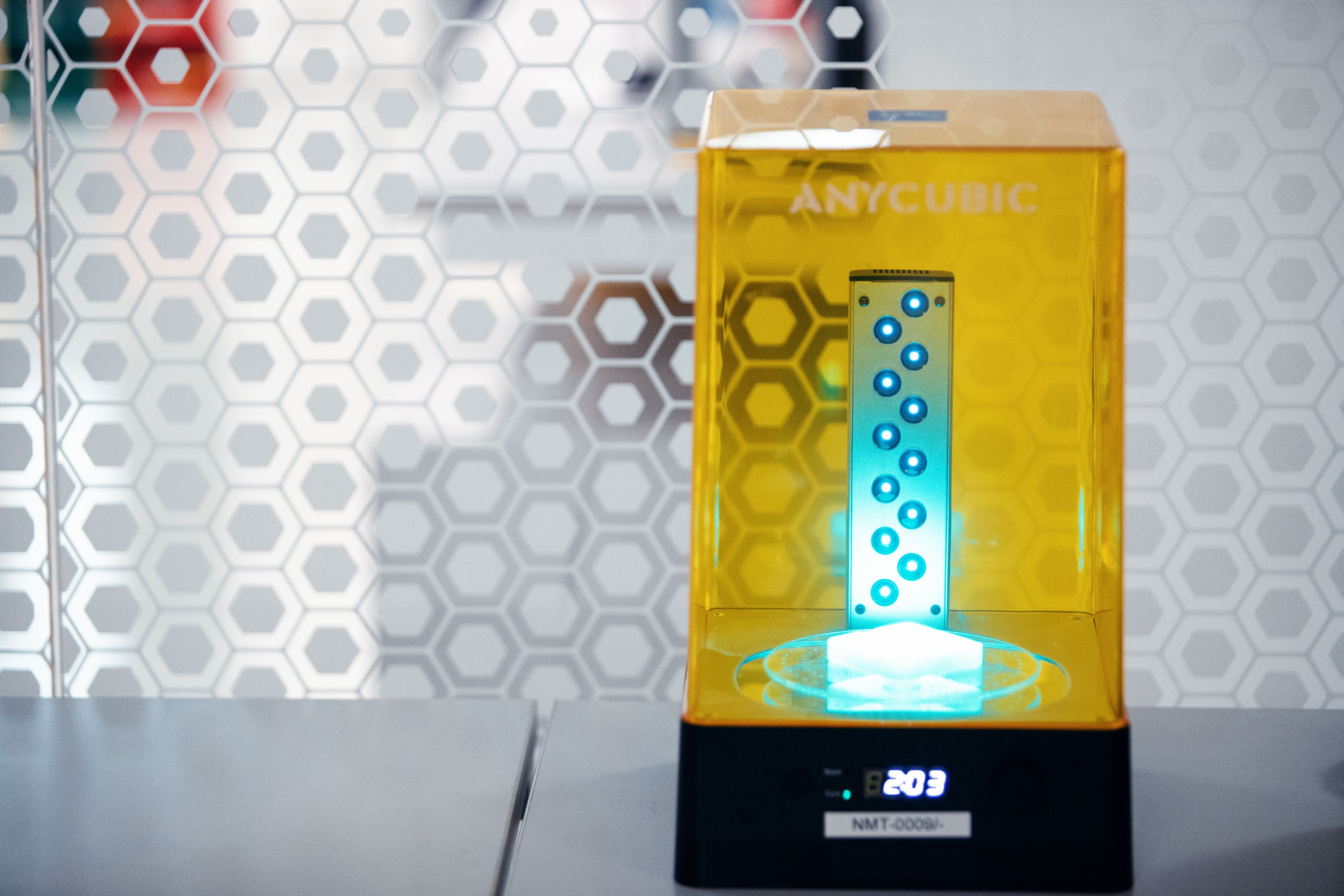 3D-printer med ett orange glas, i vilken det finns ett lysande blått ljus