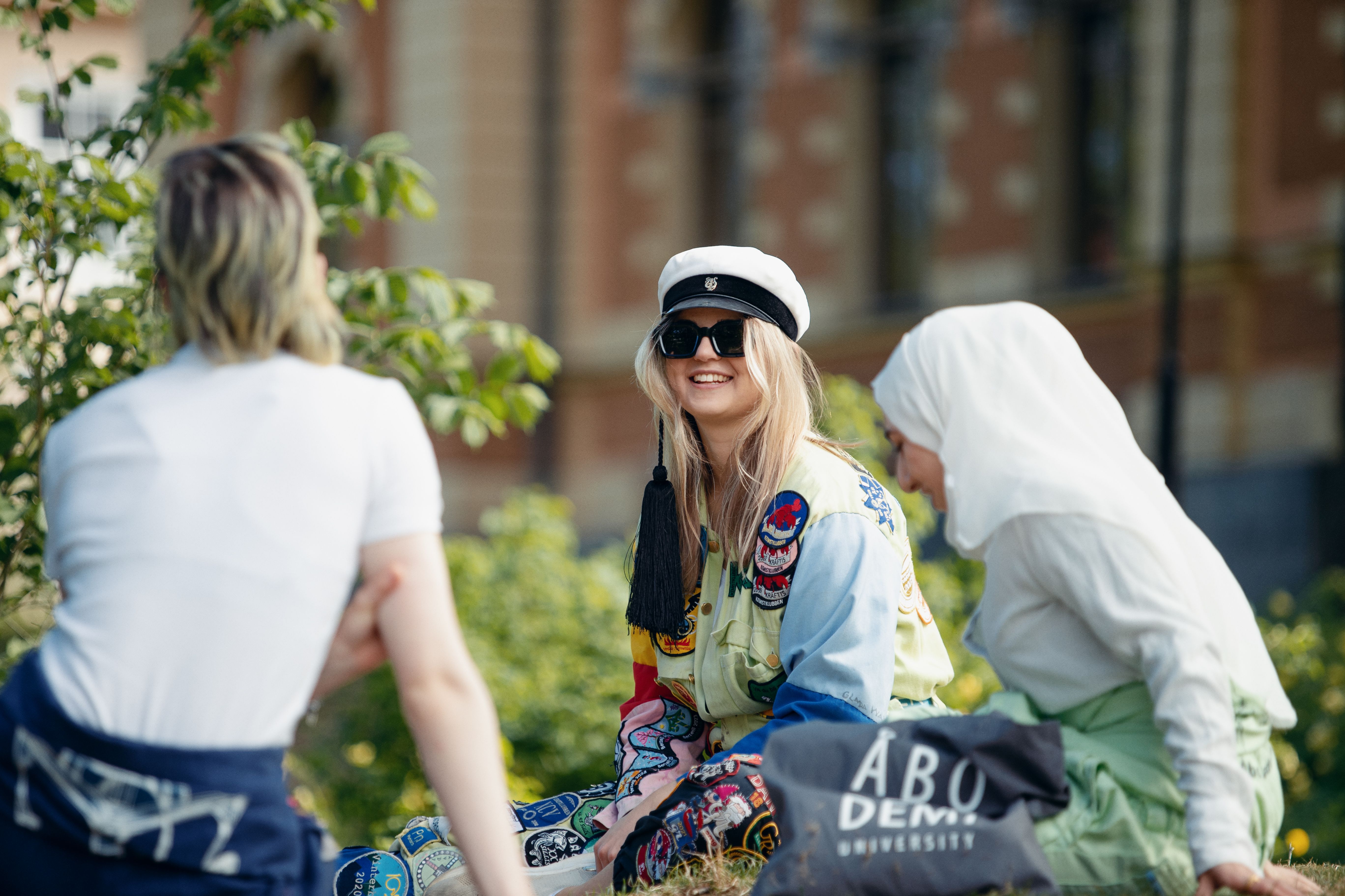 En grupp glada studerande i halare på piknik i en park