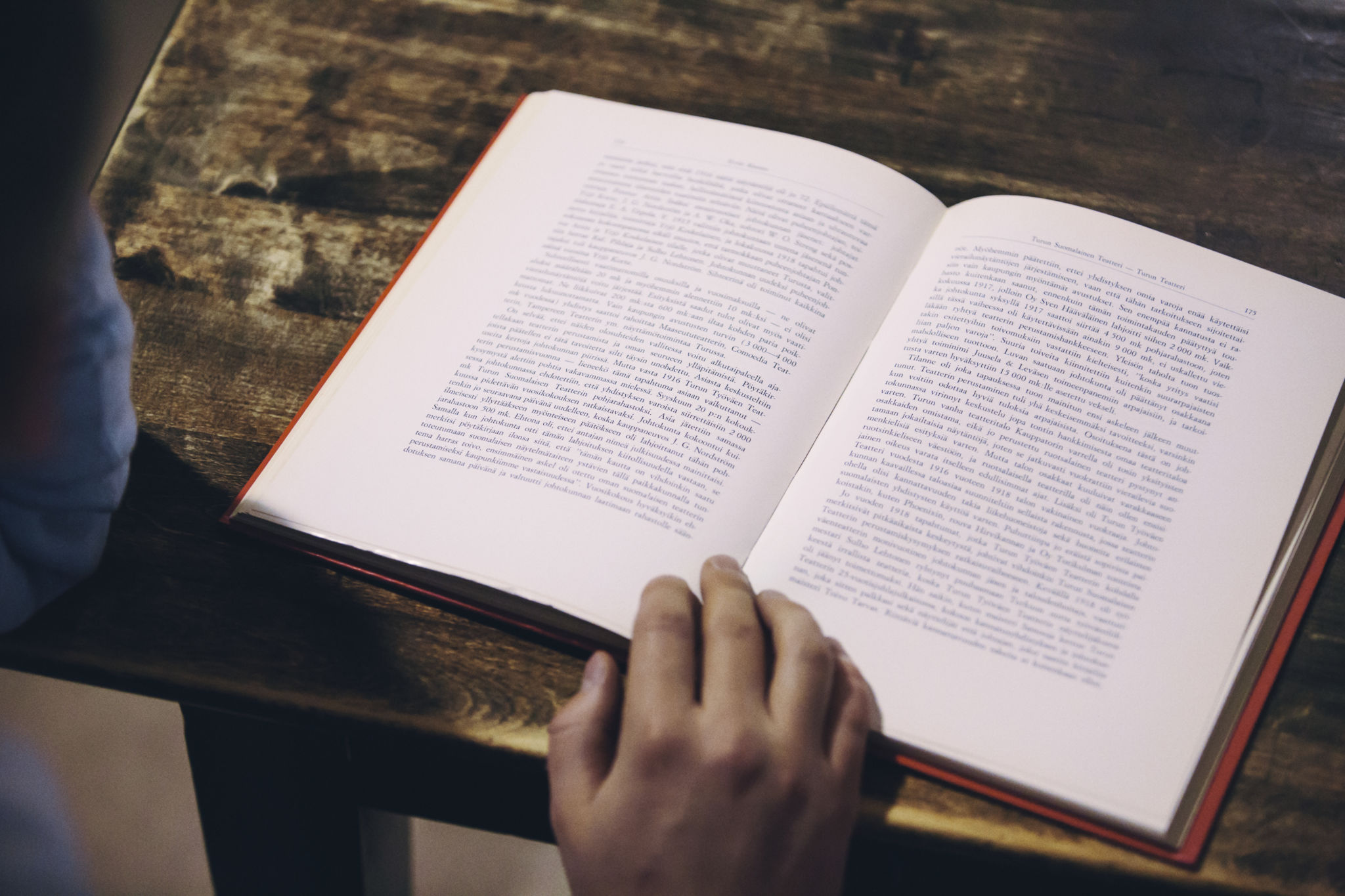 Uppslagen bok, hand.